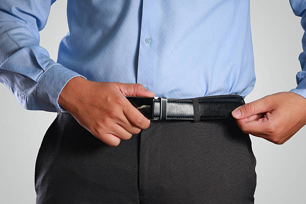 businessman tightening his belt - waistband imagens e fotografias de stock
