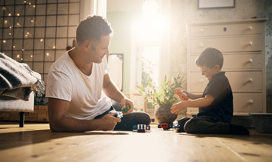 Shot of a little boy and his father playing with toys together at home