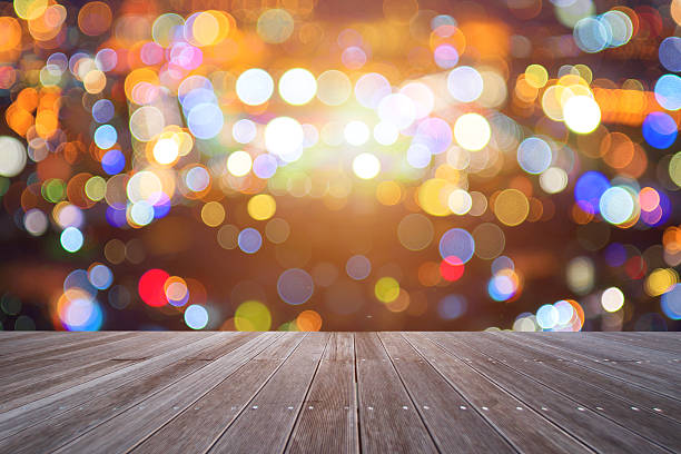 istock Empty wooden table over blurred light colorful bokeh 620005256