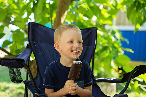 istock Happy blond kid eating chocolate ice cream bar 620365940