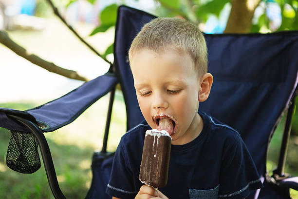 entzückende kleine junge essen eis pops in haus garten - child chocolate ice cream human mouth stock-fotos und bilder