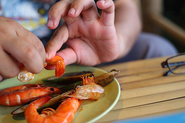 Hand of man peeled shrimps on the plate