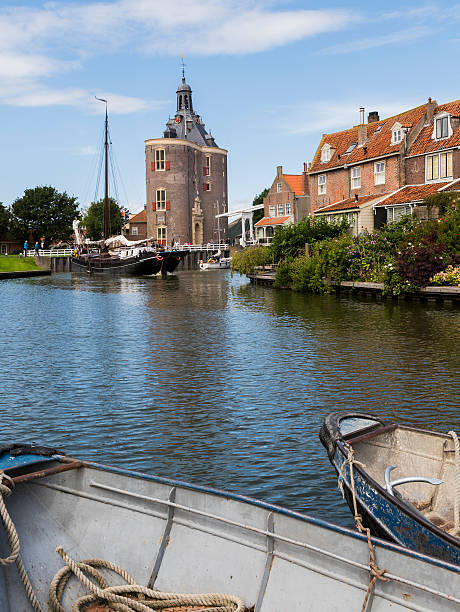 Enkhuizen, The Netherlands - August 9, 2016: Ship in the harbor of Enkhuizen with old houses, drommedaris and rowing boats.