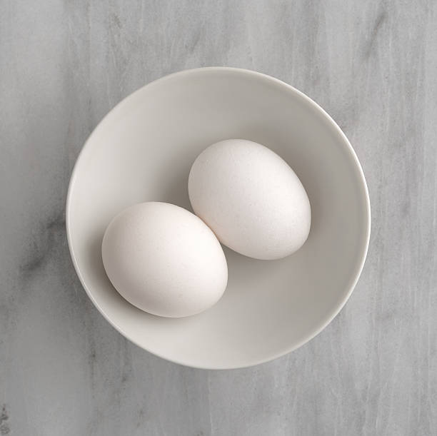 istock Two eggs in a bowl atop a marble cutting board. 620372270