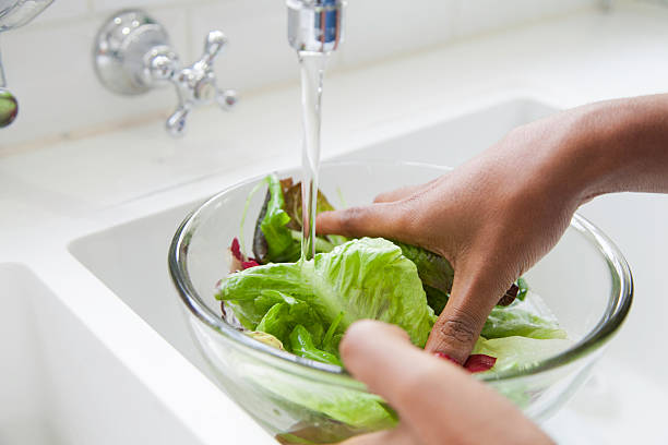 African female rinsing lettuce.