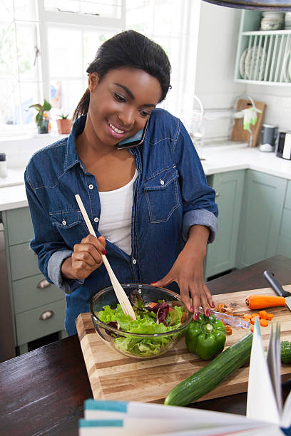 istock African female on the phone while making lunch. 620379126