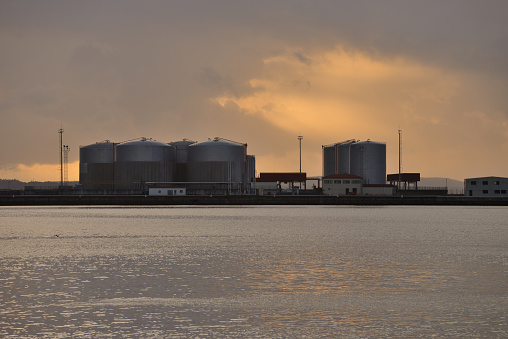 image of industrial repositories for oil and gas in the harbor at sunset