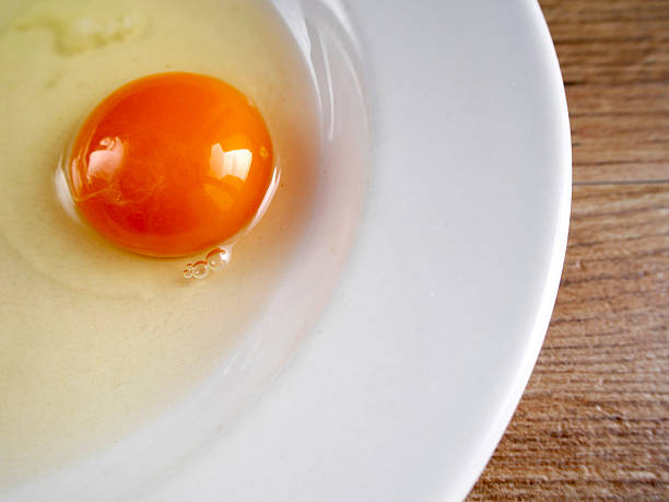 istock Yolk of egg in a plate on wood background 620380548