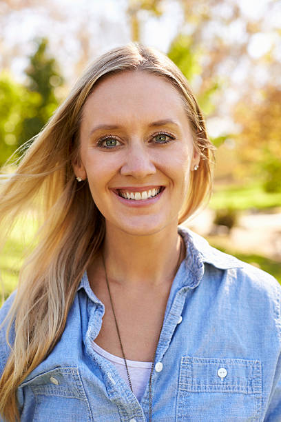 istock Mid thirties white woman smiling to camera in park, vertical 620382062