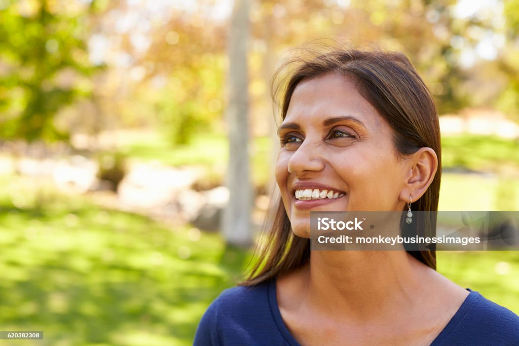 Smiling mixed race woman in park looking away from camera Women Stock Photo