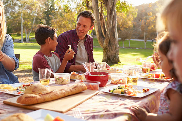 istock Two families having a picnic at a table in a park, 620382380