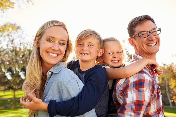 istock Parents carry their two young kids piggyback in a 620382488