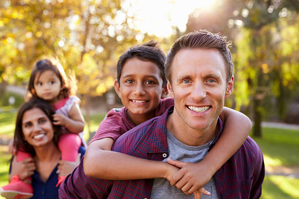 istock Mixed race parents carry kids piggyback, selective focus 620382490