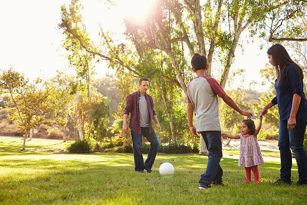 istock Young mixed race family playing with ball in a park 620382784