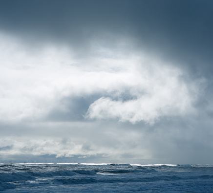 Dramatic cloudy sky over dark water ripple surface sea, sunlight, back light, photomerge