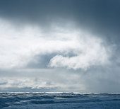 Dramatic cloudy sky over dark water ripple surface sea, sunlight