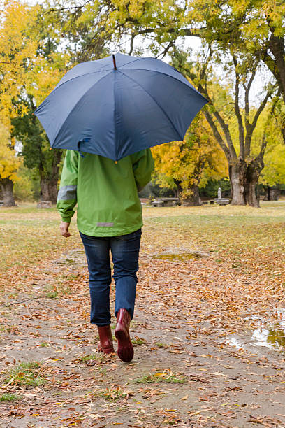 istock Woman walking with an umbrella in a park 620391514