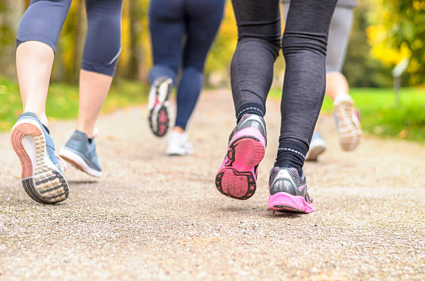 gruppe junger frau joggt gemeinsam in einem park - gehen sportdisziplin stock-fotos und bilder