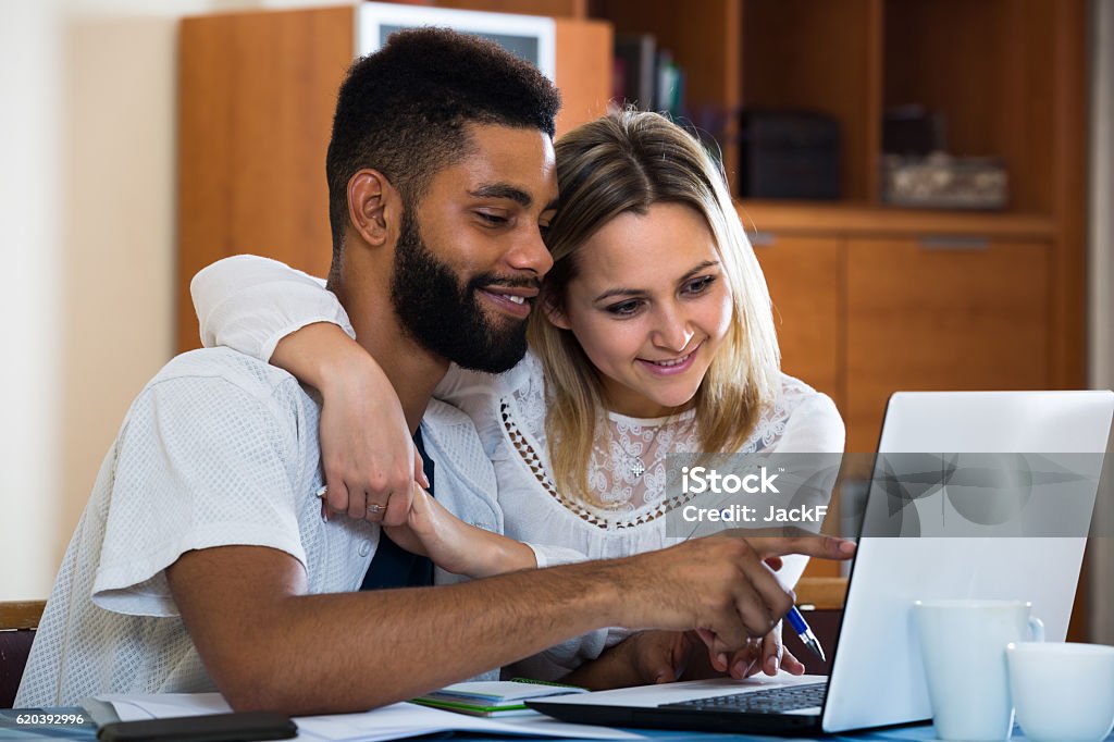 Couple filling document online Young couple filling forms of banking application in domestic interior. Focus on guy Couple - Relationship Stock Photo