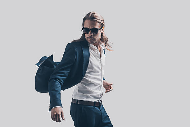 Feeling free and comfortable in his style. Handsome young man in full suit and sunglasses moving in front of grey background metrosexual stock pictures, royalty-free photos & images