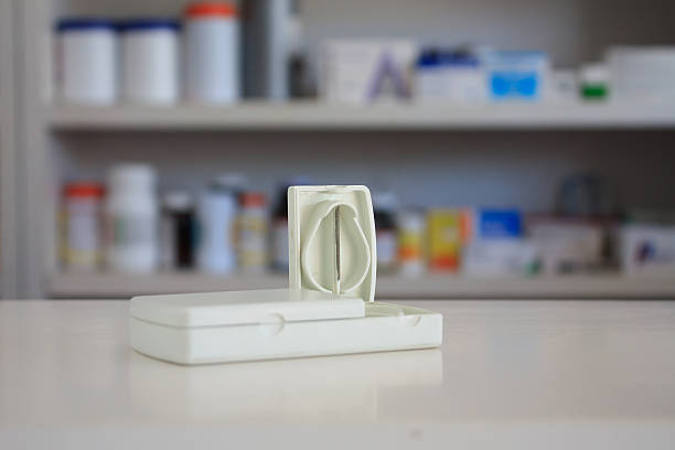 tablet cutter with blur shelves of drug in the pharmacy tablet cutter with blur shelves of drug in the pharmacy drugstore background over the counter meds stock pictures, royalty-free photos & images