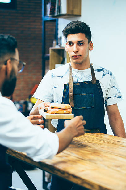 istock Young seller with sandwich 620398936