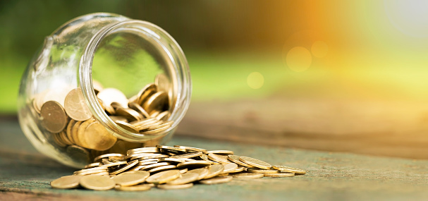 Golden coins in a glass jar - website banner of money savings concept