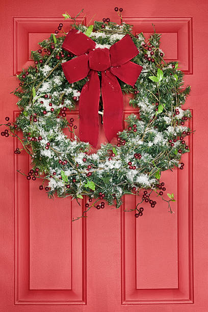 istock Christmas Wreath Hanging on Red Front Door 620402656