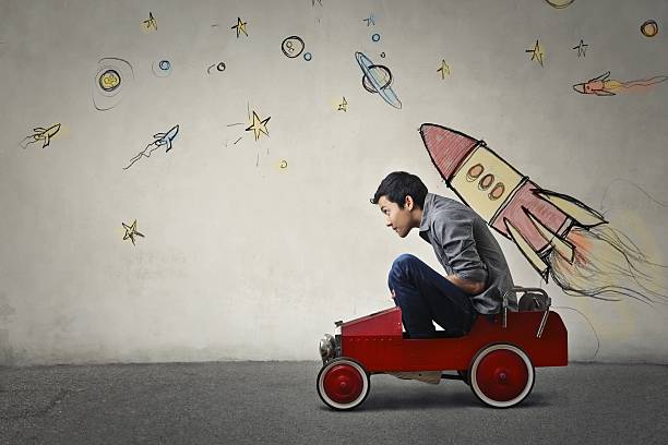 To infinity and beyond The portrait of a young Asian guy in a red toy car in front of a gray wall with spaceship and planets. growth occupation business support stock pictures, royalty-free photos & images
