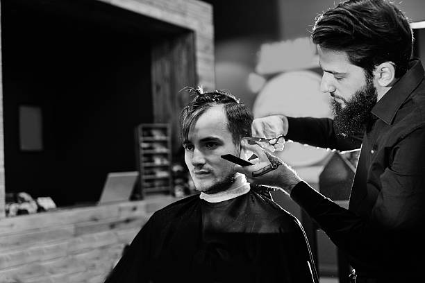 istock Male hairdresser cuts client with scissors 620404644
