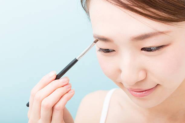 Woman applying makeup Woman applying makeup lash and brow comb stock pictures, royalty-free photos & images