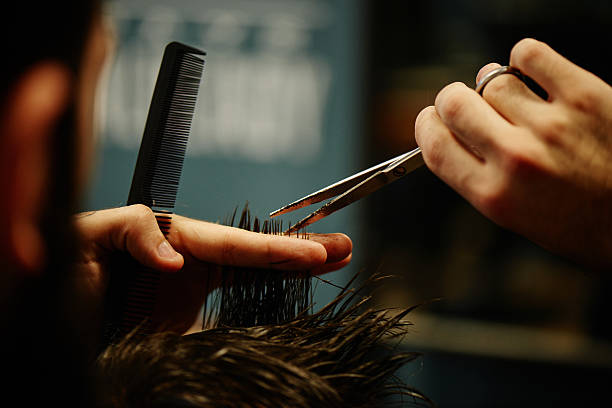 istock Hands the in the process of cutting hair with scissors 620406210