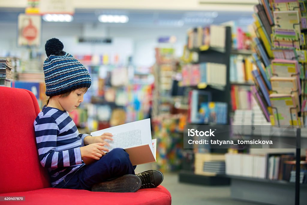 Adorable niño pequeño, niño, sentado en una tienda de libros - Foto de stock de Niño libre de derechos