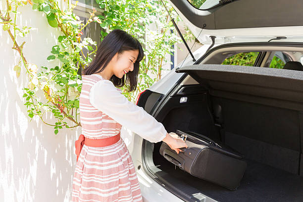istock Japanese woman loading suitcase into the trunk of a car 620412092