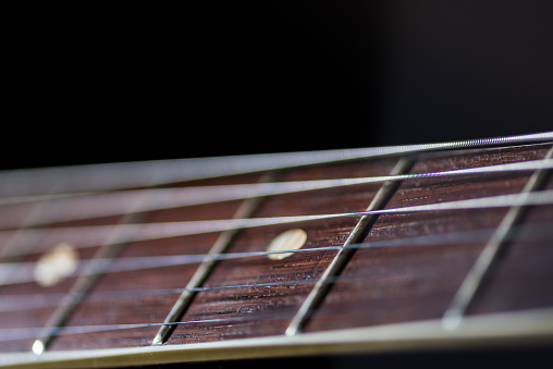 guitar fret board and strings with the body of the guitar in the background
