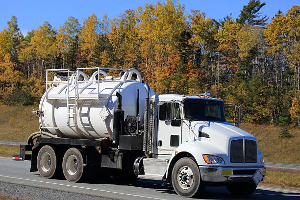 Sewage  truck on an interstate, trees in background.