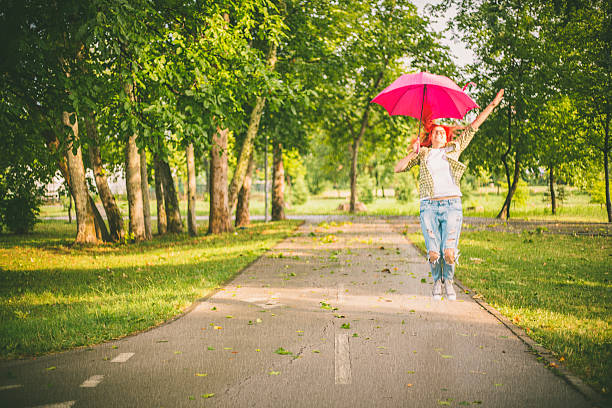 istock happy young woman jumping with umbrella 620698236