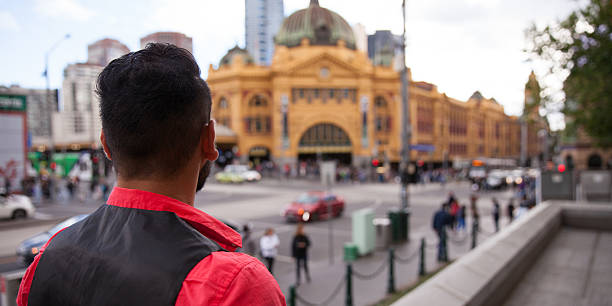 Rear view of a young man as he looks across to Flinders Street Station. Melbourne, Australia.