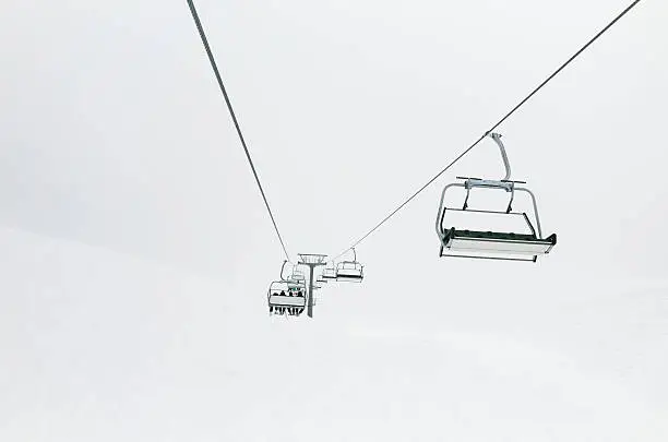 Photo of Skiers on the chair lift ropeway winter resort siluete, clouds