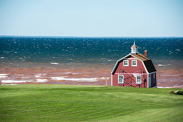 Red barn shaped home and farm along PEI coastline.