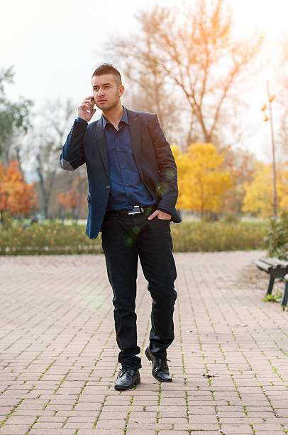 istock Young man with mobile phone in the autumn park 620703714