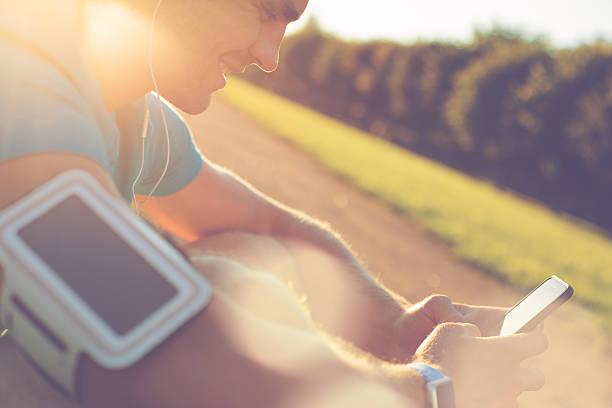 atleta alegre usando smartphone no parque - set goals audio - fotografias e filmes do acervo