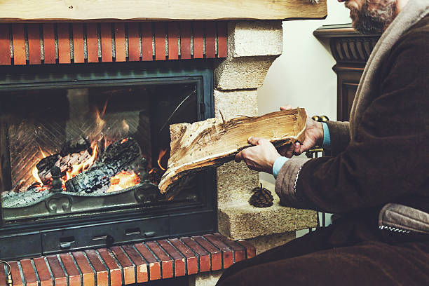 istock man with beard wearing bathrobe puts log in burning fireplace 620704462