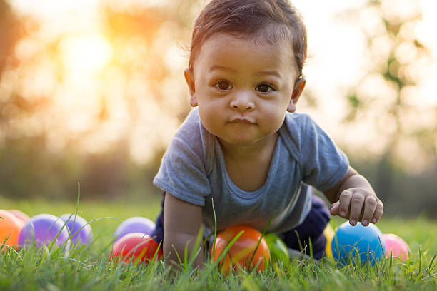 Cute asian baby crawling in the grass and colorful ball Cute asian baby crawling in the green grass and colorful ball - Sunset filter effect evening ball photos stock pictures, royalty-free photos & images