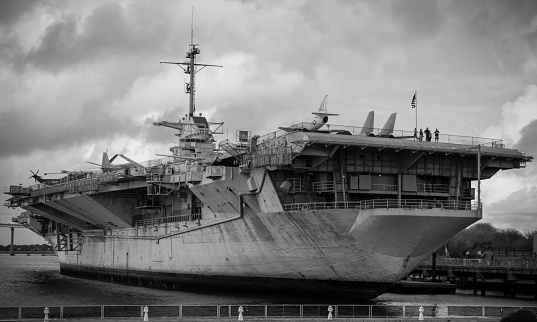 Black and white photo of a Naval ship sitting in a eastern United States Port. 