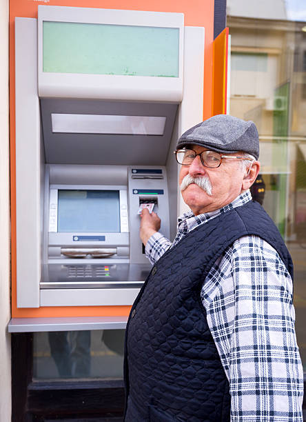 istock elderly man inserting credit card to ATM 620711398