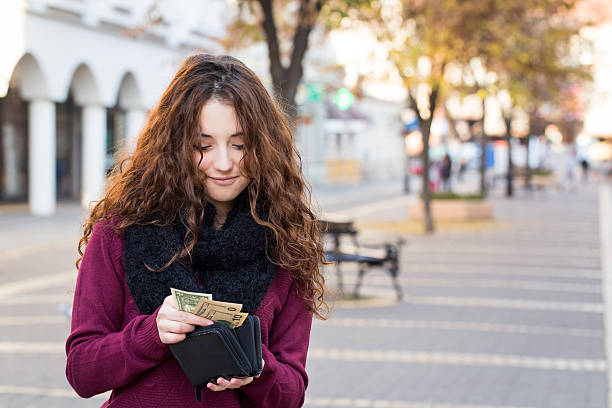 jeune femme cliente prenant de l’argent du portefeuille dans la rue - teenager retail shopping consumerism photos et images de collection