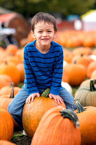 Cute young boy sitting on a pumpking and smiling