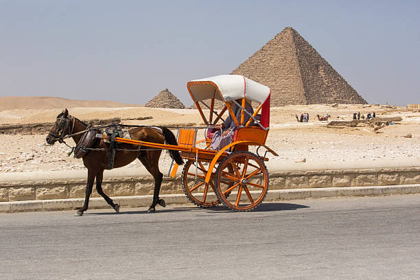 Giza, Egypt - July 18, 2016: A horse-drawn carriage rides by the Pyramid of Menkaure with one of three Queens Pyramids on it's south side, in Giza.