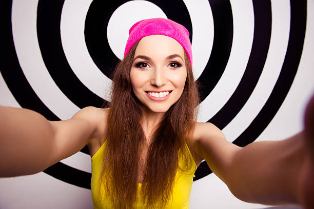 Beautiful girl with beaming smile in pink cap making selfie